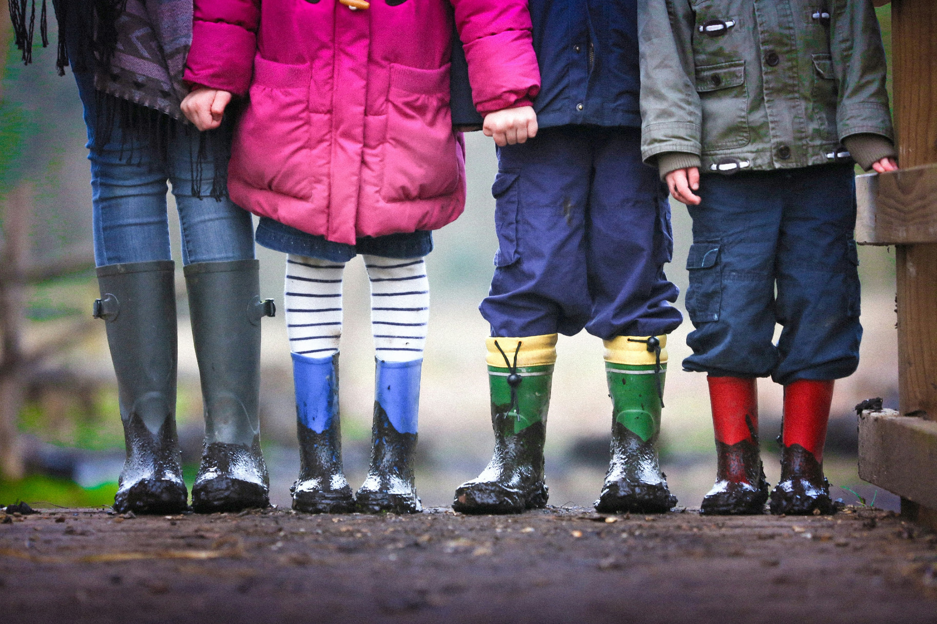 Children standing together in colorful rain boots